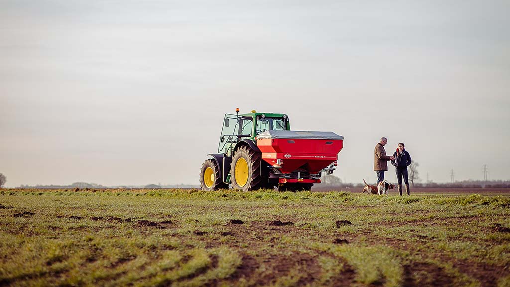 Menschen und Düngerstreuer auf Feld